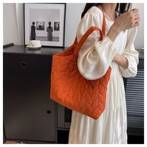 Detail der orangefarbenen Stepptasche mit Blattmuster zeigt Textur und großes Volumen