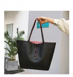 Detail of black pebbled leather tote bag with pink interior and gold ring charm