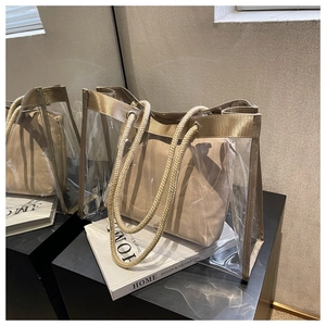 Detailed close-up of a clear PVC tote bag with champagne gold trim and rope handles