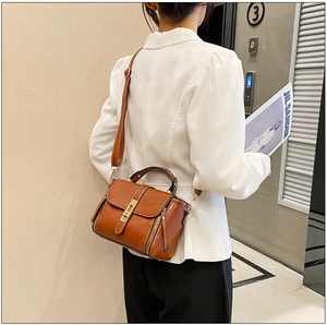 Borsa a mano in pelle cerata caramello indossata a tracolla in un contesto lifestyle