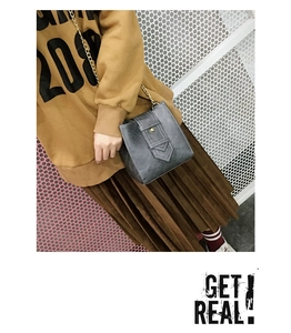 Detail of grey matte leather crossbody bag with metal ring buckle and gold chain strap