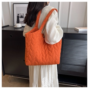 Detailansicht der großen orangefarbenen Stepptasche mit einzigartigen Blattstichmustern