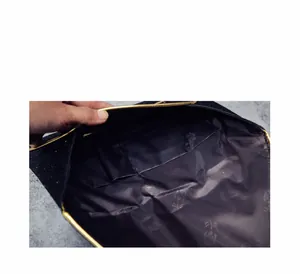 Detail of evening clutch bag showing purple floral lining and golden metal frame edge