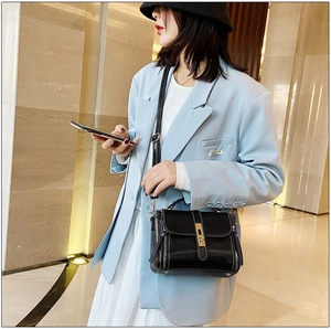 Borsa a mano chic in pelle cerata nera con finiture dorate e nappine, vista stile street fashion
