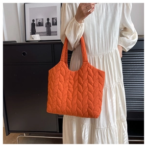 Leuchtend orangefarbene Stepp-Tote-Bag kombiniert mit einem weißen Faltenkleid im Innenraum