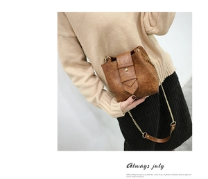 Detail view of retro brown bucket bag featuring metal chain strap and rivet decoration