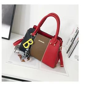 Détail du sac cabas bicolore en cuir grainé avec pendentif B jaune et sangle logo