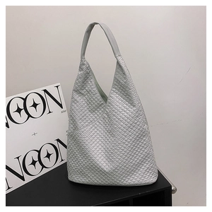 Detail einer grauen Schultertasche mit geometrischer Prägung und Dreiecksstruktur