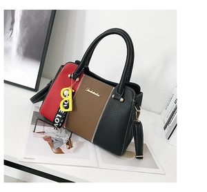 Gros plan du sac à main tricolore avec détails dorés et pendentif perle élégant