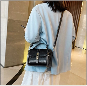 Vista posteriore di una modella in blazer azzurro con borsa in pelle cerata nera