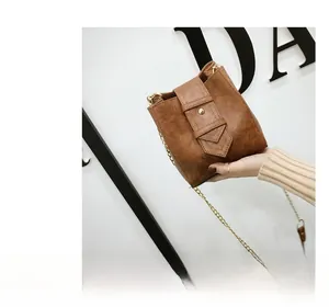 Detailed view of a brown bucket crossbody bag featuring textured PU leather and a gold chain