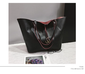 Detail of black pebbled leather tote bag with pink interior and gold ring buckle