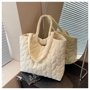 Detail der gesteppten beigen Shopper-Tasche mit Magnetverschluss und Blattmuster