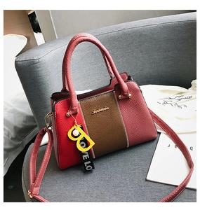 Détail du sac à main tricolore en cuir grainé avec pendentif B jaune et sangle décorative
