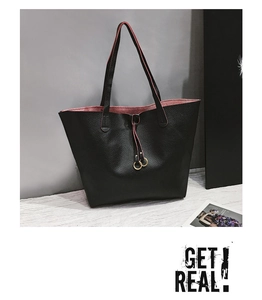 Detail of black pebbled leather tote bag with dark red lining and golden metal rings