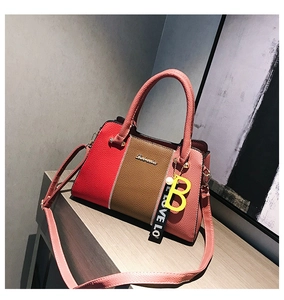 Détail de la texture en cuir tricolore et du logo métallique sur le sac à main de mode