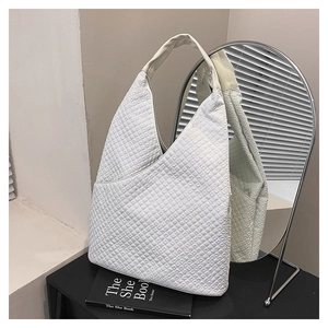 Detaillierte Nahaufnahme einer weißen gesteppten Hobo-Tasche mit Karomuster auf einem Tisch