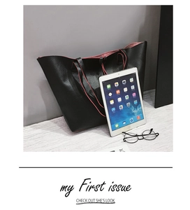 Detail of black pebbled leather tote bag with red lining and matching inner pouch