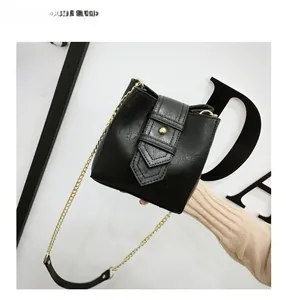 Detail of black textured PU leather bucket bag with gold buckle and chain shoulder strap