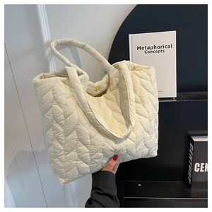 Detailansicht der cremefarbenen Stepptasche mit Blattmuster-Nähten und Druckknopf aus Gold