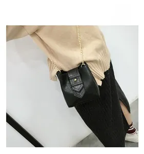 Detail of a black mini bucket bag with gold chain strap worn by a model on side