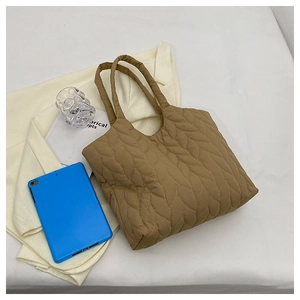 Detail einer braunen Stepp-Tote-Bag mit Blattmuster-Nähten und weicher, voller Textur