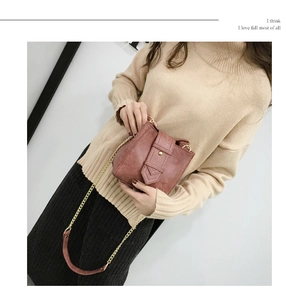 Detail of vintage pink leather crossbody bag with gold chain strap on beige knit sweater