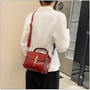 Borsa a mano rosso scuro in pelle cerata con chiusura metallica portata a tracolla