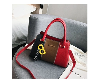 Détail du sac à main en cuir multicolore avec logo en métal et breloque sur canapé