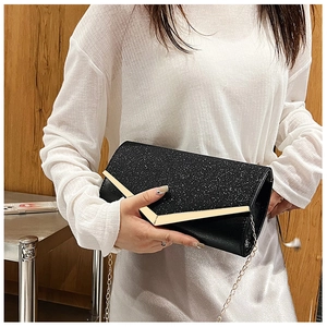 Close-up of black glitter evening clutch featuring a stylish gold V-shaped metal trim