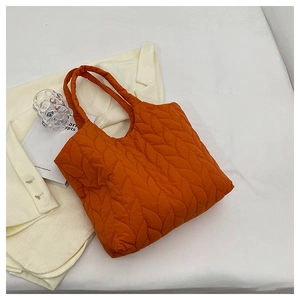 Detailansicht einer orangefarbenen gesteppten Nylontasche mit Wellenmuster und Tragegriffen