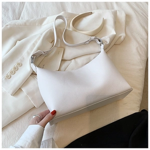 Dettaglio della borsa in pelle litchi color crema su una giacca da abito bianca