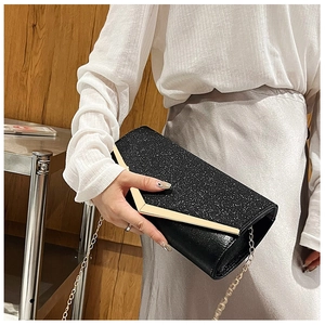 Close-up of black glitter evening clutch with V-shaped gold metal trim held by a model