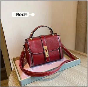 Dettaglio della borsa rossa in pelle cerata con fibbia in metallo vintage e cuciture bianche