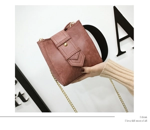 Close-up of vintage pink leather crossbody bag with gold buckle and chain strap