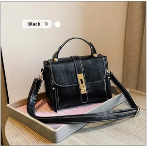 Dettaglio della borsa in pelle cerata nera con cuciture bianche a contrasto e finiture dorate