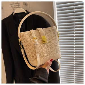 Detail of white straw bucket bag featuring chevron texture and gold twist lock closure
