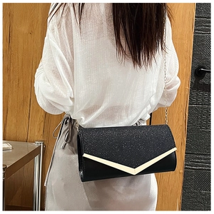 Detail of black glitter evening clutch bag with gold V-shape metal trim and chain strap
