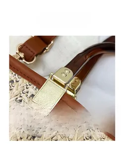 Close-up of golden metal clasp and premium brown leather on a woven straw tote bag