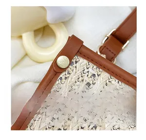 Close-up of woven straw tote bag with brown leather trim and golden metal rivet detail