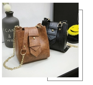 Detail view of mini bucket bags in brown and black with gold chains and retro leather texture