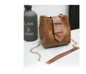 Detailed macro view of the vintage brown textured leather bucket bag with gold chain