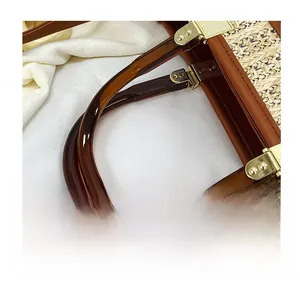 Detail of hand-woven beige straw bag with amber resin handle and gold metal hardware