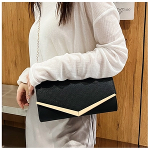 Detail of black envelope clutch featuring woven texture and gold V-shaped metal trim
