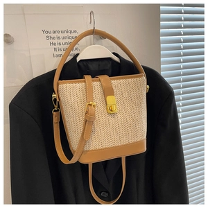 Detailed close-up of straw bucket bag with brown leather trim and golden metal lock