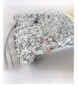 Gros plan des paillettes argentées sur un sac seau à cordon avec finition métallisée