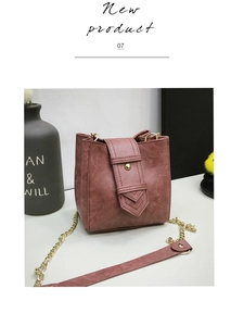 Close-up of arrow-shaped leather flap and round gold buckle on pink bucket bag