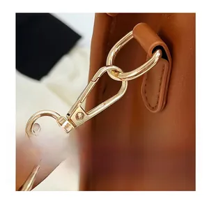 Close-up of golden metal hook and leather texture on a handmade woven tote bag