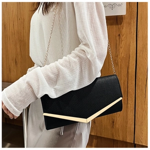 Detail of black envelope clutch bag with gold V-bar metal accent and chain strap