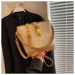 Close-up of woven straw bucket bag featuring a brown leather closure and gold twist lock